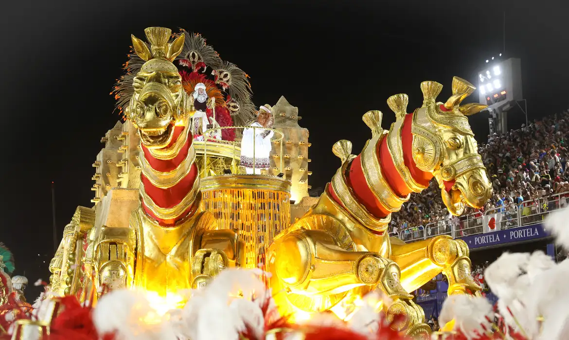 Carro alegórico dourado com cavalos gigantes desfilando no Carnaval do Rio
