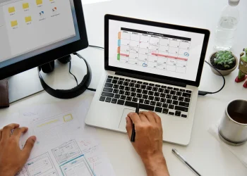 Pessoa organizando compromissos em um calendário mensal no notebook, ilustrando o planejamento de feriados prolongados em 2026.