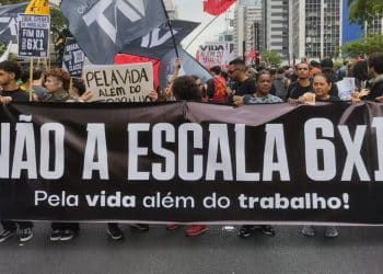 Trabalhadores de diversos setores, como comércio e serviços, segurando cartazes em protesto pelo fim da escala 6x1, com destaque para a demanda por mais tempo de descanso e saúde mental.