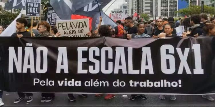 Protesto contra a escala 6x1, com manifestantes segurando faixa e cartazes pedindo mais tempo livre e qualidade de vida para os trabalhadores.