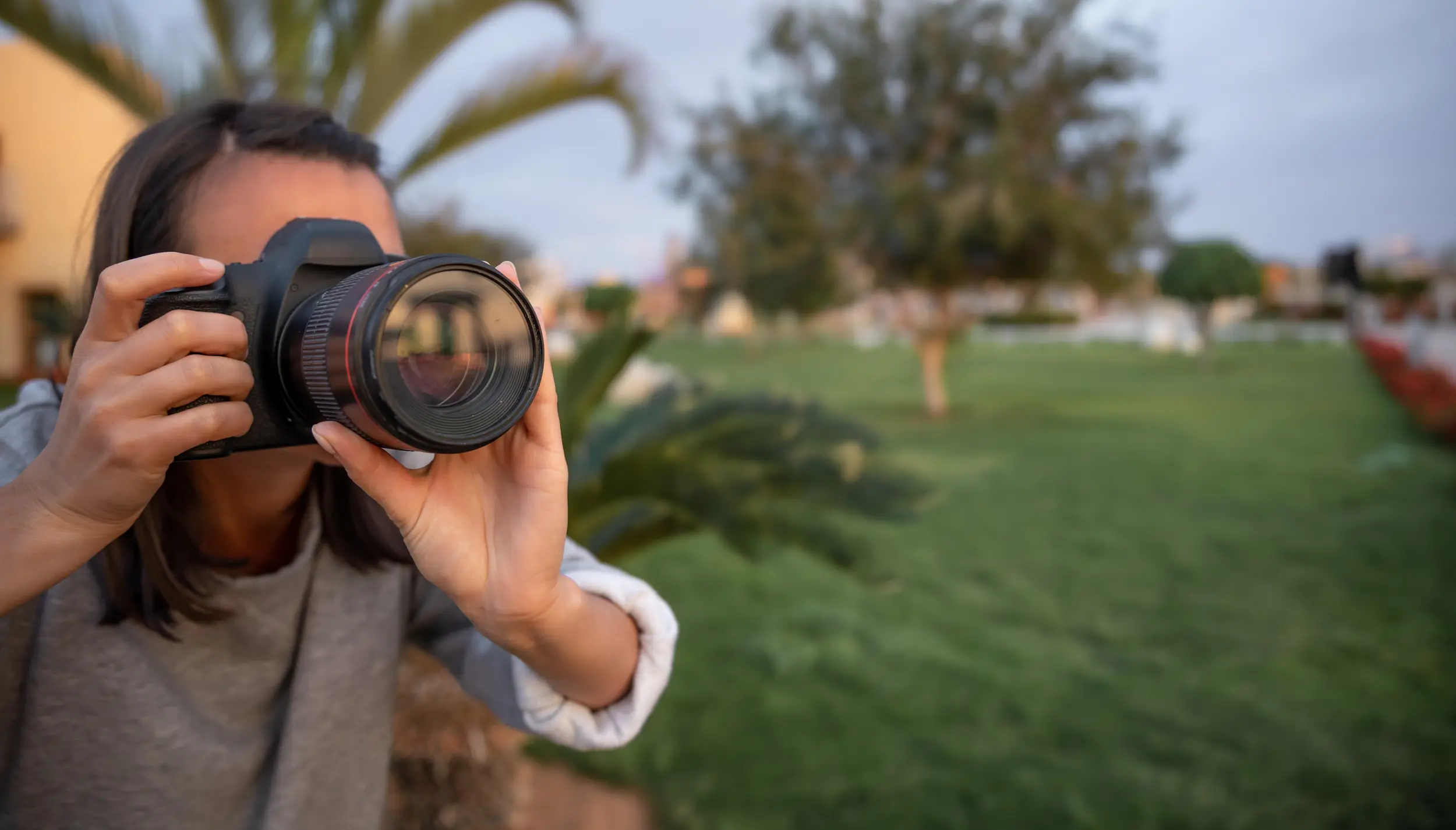 Pessoa tirando uma foto com câmera profissional, destacando o ato de fotografar em ambiente ao ar livre.