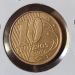 Visão frontal de uma moeda de 10 centavos de 2010, com cor bronzeada, protegida em um suporte de papel branco (coin holder). A imagem foca no numeral "10" e na data "2010" em relevo, evidenciando o brilho metálico e os detalhes da cunhagem.