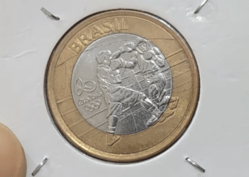 Moeda de 1 real brasileira comemorativa das Olimpíadas Rio 2016, exibindo a modalidade boxe, em uma cápsula protetora para colecionadores.