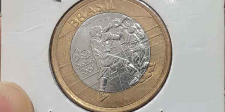 Moeda de 1 real brasileira comemorativa das Olimpíadas Rio 2016, exibindo a modalidade boxe, em uma cápsula protetora para colecionadores.