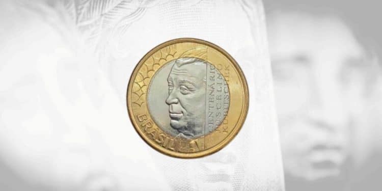 Visão frontal da moeda de 1 Real comemorativa do centenário de Juscelino Kubitschek, mostrando o perfil do ex-presidente no núcleo de prata e o anel dourado com a inscrição "BRASIL".