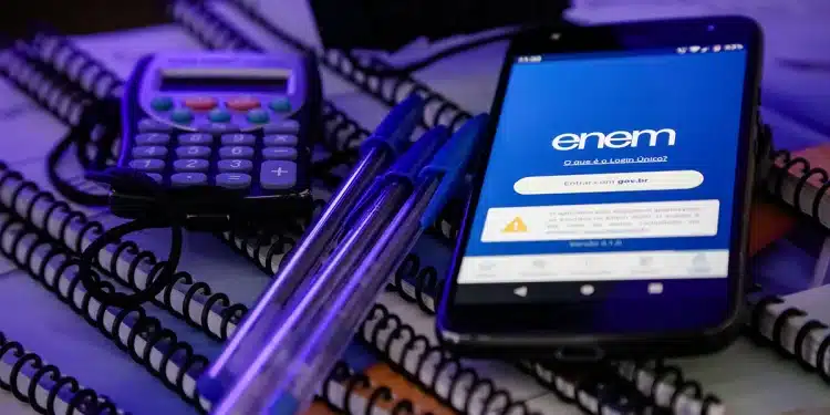 Calculadora, canetas e smartphone com aplicativo do Enem em destaque sobre cadernos.