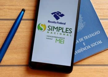 Tela de celular exibindo logo da Receita Federal, Simples Nacional e MEI, com fundo da carteira de trabalho.