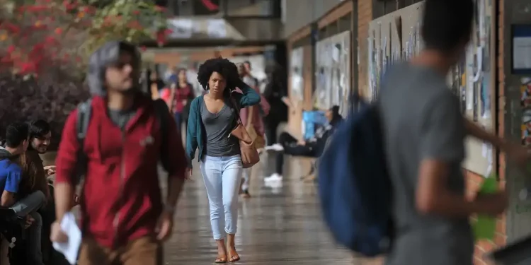 Estudante caminha por corredor universitário representando o desafio de atrair jovens para a carreira docente no Brasil.