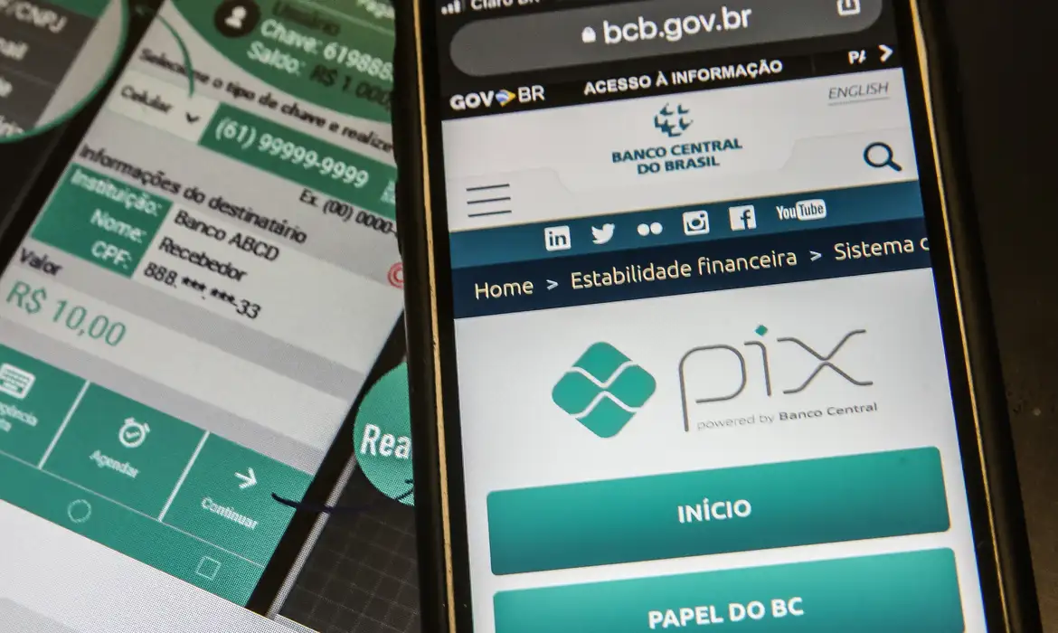 Visão em perspectiva de um smartphone exibindo o site oficial do Banco Central sobre o Pix, ao lado de outra tela com detalhes de uma transação bancária em andamento.
