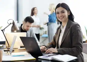 Profissional de escritório trabalhando em frente ao computador, em um ambiente corporativo moderno.