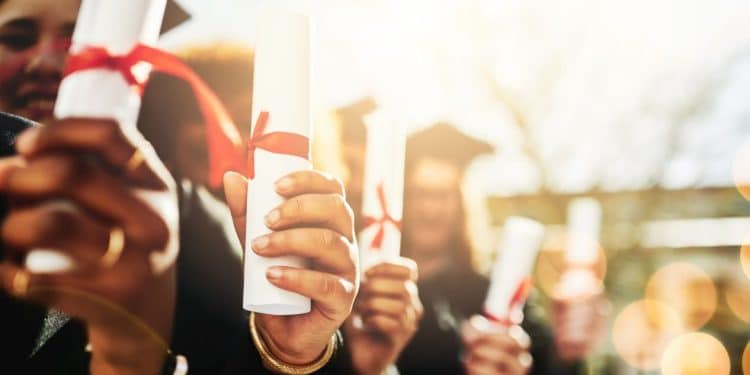 Grupo de formandos segurando seus diplomas, simbolizando a conquista do ensino superior, mas também os desafios de um mercado de trabalho competitivo.