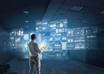 Homem observando telas holográficas com gráficos e dados, simbolizando profissões tecnológicas e analíticas em crescimento silencioso.