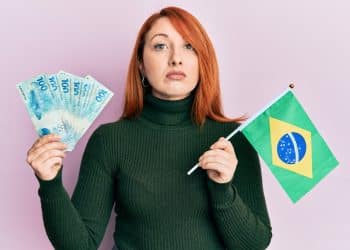 Mulher segurando dinheiro e bandeira do Brasil.