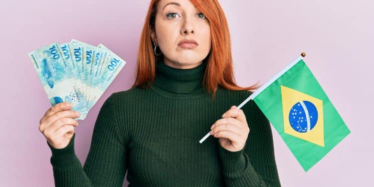 Mulher segurando dinheiro e bandeira do Brasil.