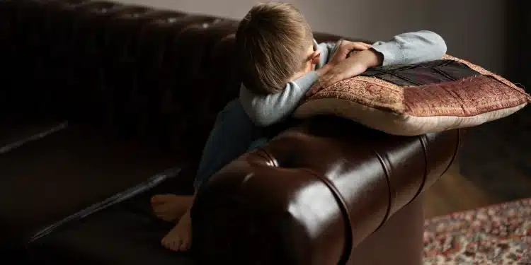 Menino de cabeça baixa sobre um sofá, simbolizando o sofrimento causado por frases negativas de pais tóxicos