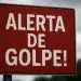 Placa vermelha com os dizeres 'Alerta de golpe!' em branco.