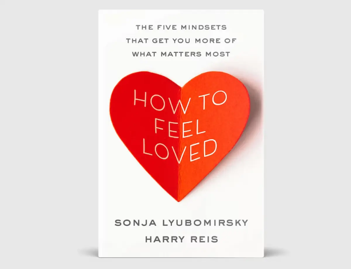 Capa do livro 'How to Feel Loved' de Sonja Lyubomirsky e Harry Reis, com o título em uma fonte clara e um coração vermelho, abordando a importância do amor para a felicidade.