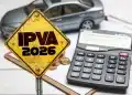 Placa amarela com a inscrição “IPVA 2026”, ao lado de uma calculadora, moedas e um carro em miniatura sobre uma mesa.