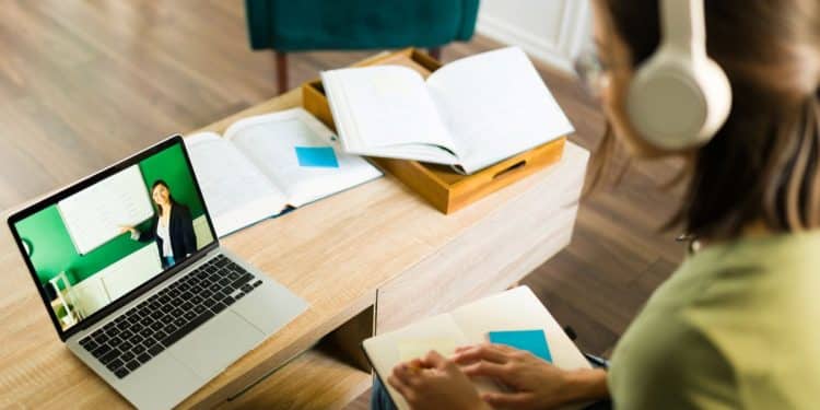 Estudante assistindo aula online em uma faculdade EaD, com laptop e fones de ouvido, representando a flexibilidade do ensino a distância no Brasil.