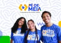 Três novos beneficiários do programa Pé-de-Meia, sorrindo e usando camisetas com o logo do programa em um fundo com formas geométricas.
