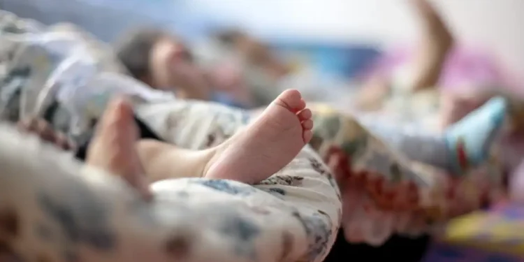 Pés de crianças deitadas em colchões cobertos por cobertores coloridos