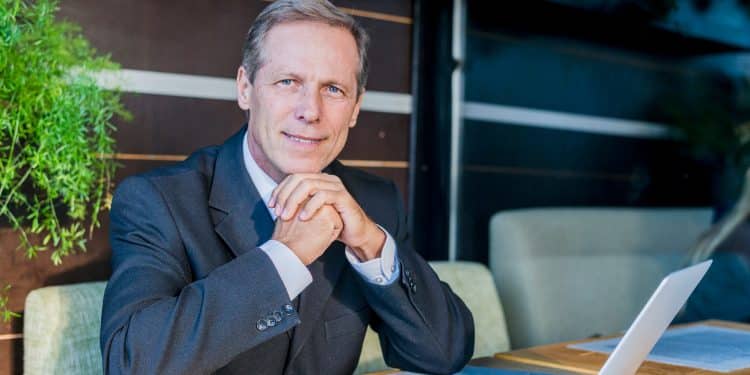 Executivo maduro acima dos 40 anos bem-sucedido com laptop representando carreiras que pagam altos salários pela experiência