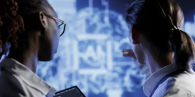 Duas pessoas analisando projeção de dados digitais em tela azul com tablet em mãos