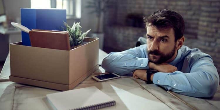 Trabalhador preocupado em escritório representa o contraste entre vagas disponíveis e pessoas sem emprego no Brasil.