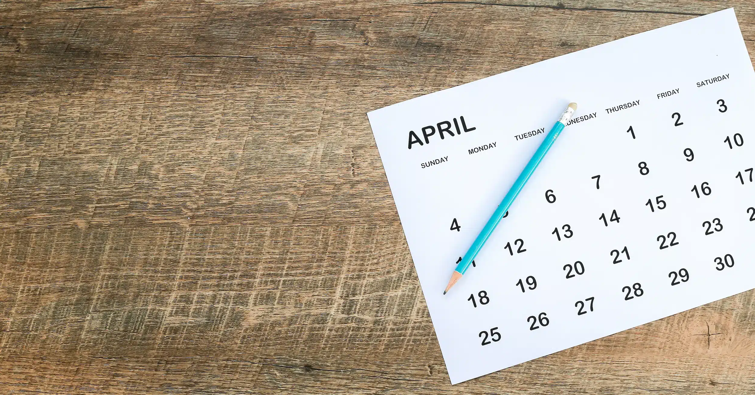 Calendário de abril de 2026 com os dias organizados e uma caneta azul em cima.