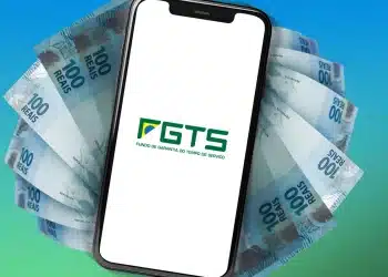 Smartphone exibindo logo do FGTS sobre leque de notas de R$ 100 em fundo azul esverdeado, representando os pagamentos do saque-aniversário do FGTS