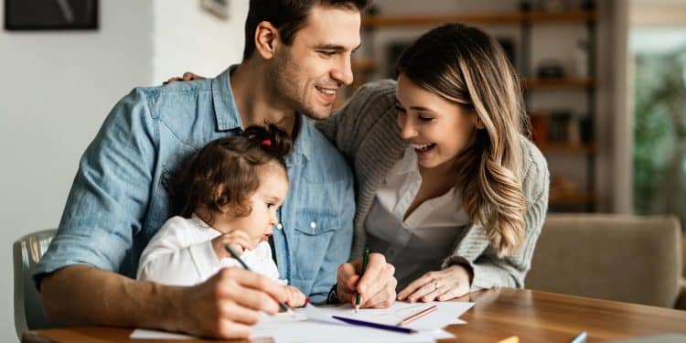 Família feliz planejando finanças juntos em casa com criança desenhando na mesa