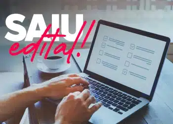 Mãos digitando em notebook com checklist na tela e xícara de café ao lado representando inscrição em concurso público