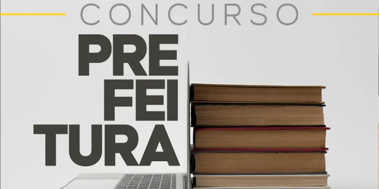 Um notebook aberto ao lado de uma pilha de livros marrons, com o texto "CONCURSO PREFEITURA" em destaque sobre um fundo cinza claro.