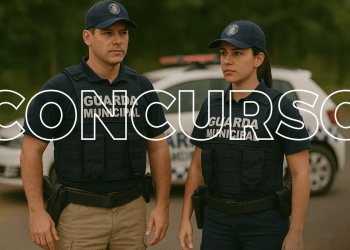 Guarda municipal masculino e feminino em frente a viatura oficial usando uniforme e colete balístico.