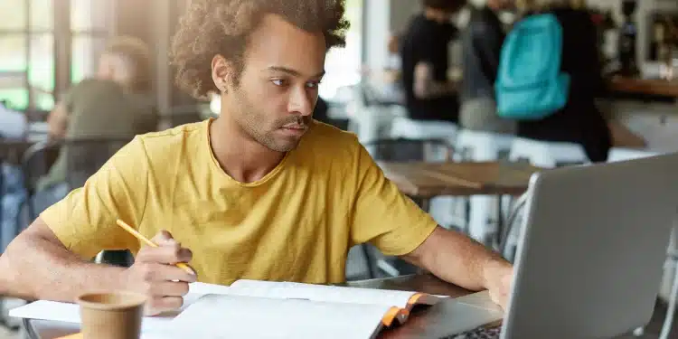 Pessoa estudando com livros e laptop, buscando aprimorar seus estudos para concursos, como os do Cebraspe.