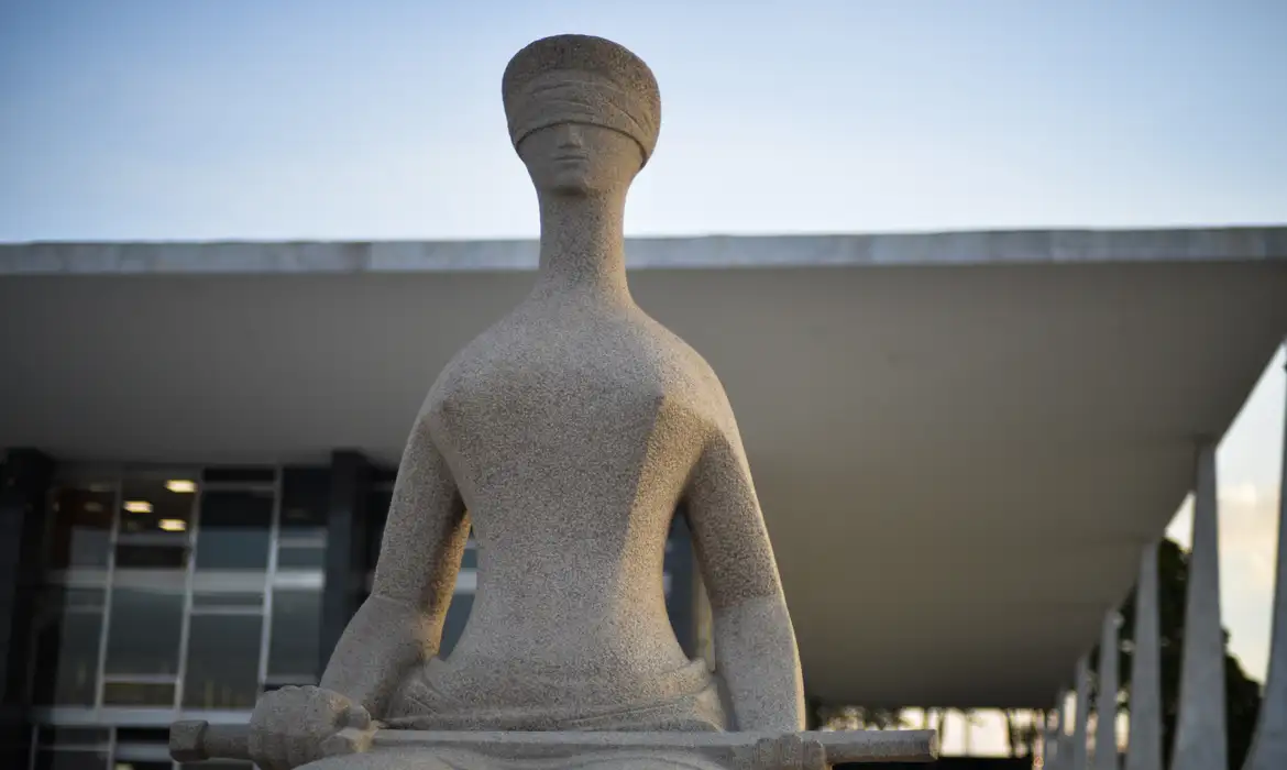 Escultura de mulher com venda nos olhos em frente ao prédio do STF ao entardecer