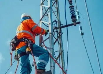 Eletricista de alta tensão trabalhando em torre de energia elétrica em grande altura