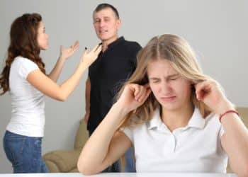 Jovem tampando os ouvidos enquanto presencia uma briga entre adultos, ilustrando o impacto da violência doméstica e trauma infantil