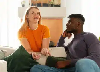 Casal conversando em um ambiente confortável, com um deles sorrindo e o outro observando atentamente.