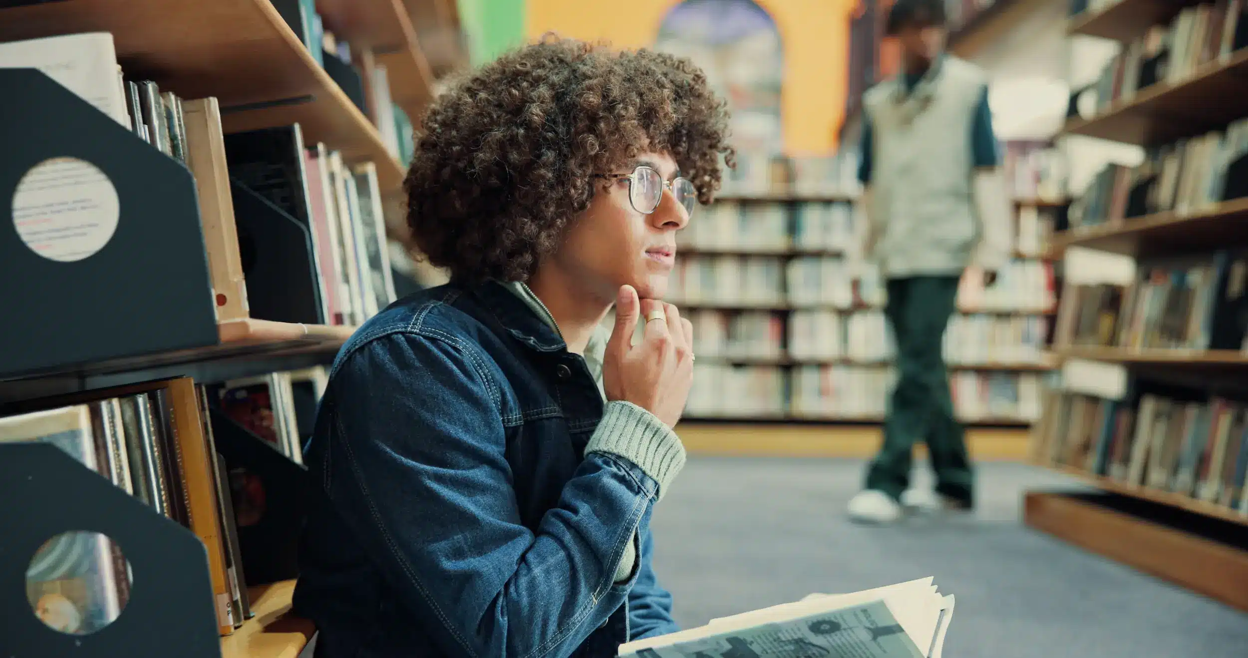 Jovem refletindo em biblioteca, pensamento profundo sobre frases de inteligência.