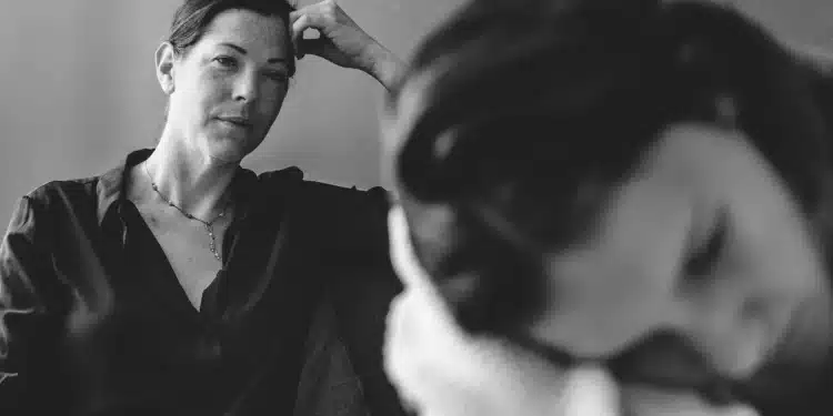 Mãe observa filha adolescente cabisbaixa durante conversa tensa em ambiente doméstico.