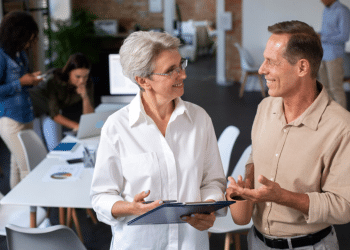 Profissionais acima de 50 anos em ambiente corporativo moderno representando recolocação no mercado de trabalho