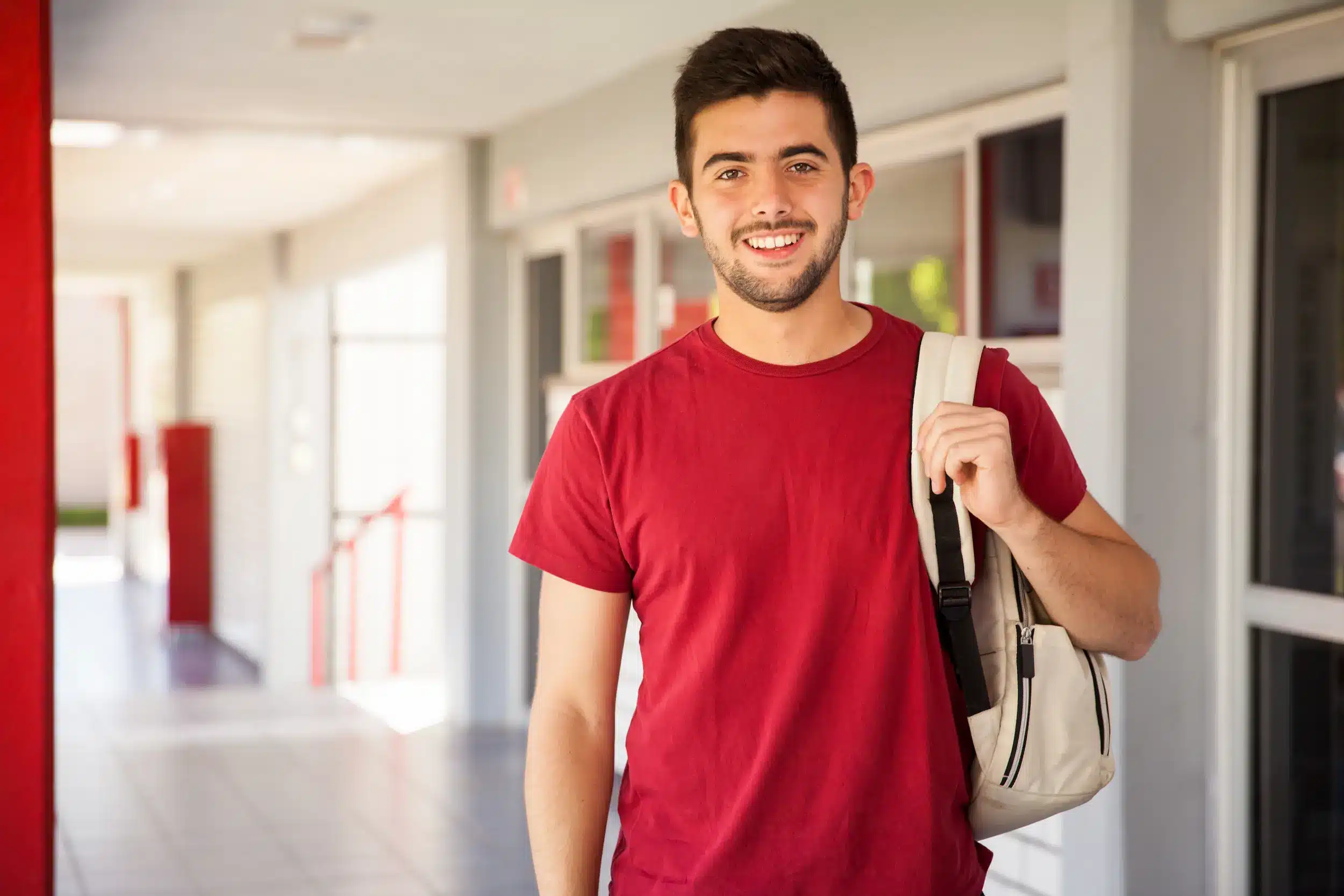Estudante sorrindo com mochila, refletindo sobre a escolha da modalidade ideal de curso, como bacharelado, licenciatura ou tecnológico.