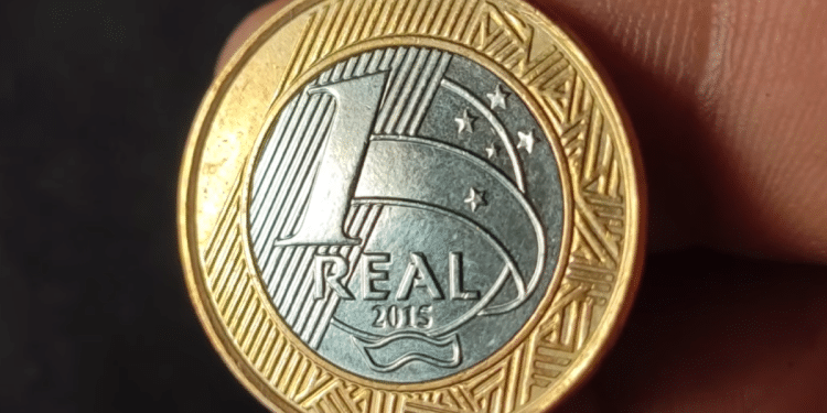 Foto em close do reverso de uma moeda de 1 real comemorativa das Olimpíadas Rio 2016, exibindo o valor "1 REAL" e o ano de cunhagem "2015" no centro do núcleo prateado.