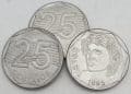 Três moedas de 25 centavos brasileiras, com uma delas virada para o anverso, mostrando a efígie da República e o ano de 1995.