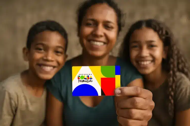 Mulher e duas crianças sorrindo seguram cartão colorido do Bolsa Família em destaque