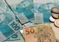 Pagamento do INSS em fevereiro com notas de real e moedas representando benefício de R$ 8.475,55.