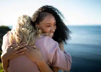 Duas pessoas abraçadas com um fundo natural e sereno, representando o cuidado e apoio mútuo em relacionamentos saudáveis.