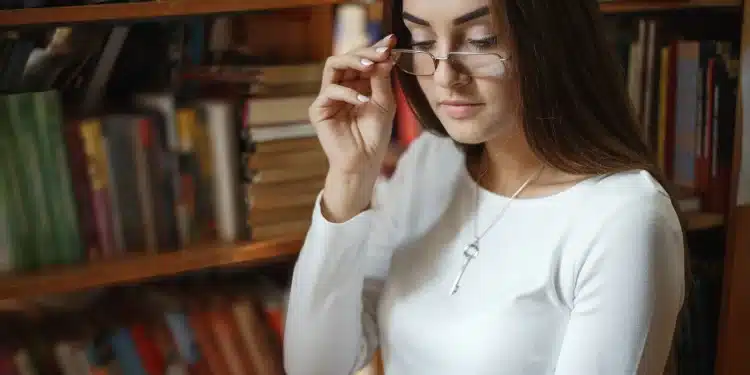 Mulher lendo livro em biblioteca, refletindo sobre frases de inteligência.