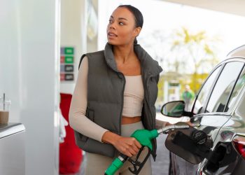 Mulher abastecendo carro em posto de gasolina com combustível mais caro devido ao aumento do ICMS